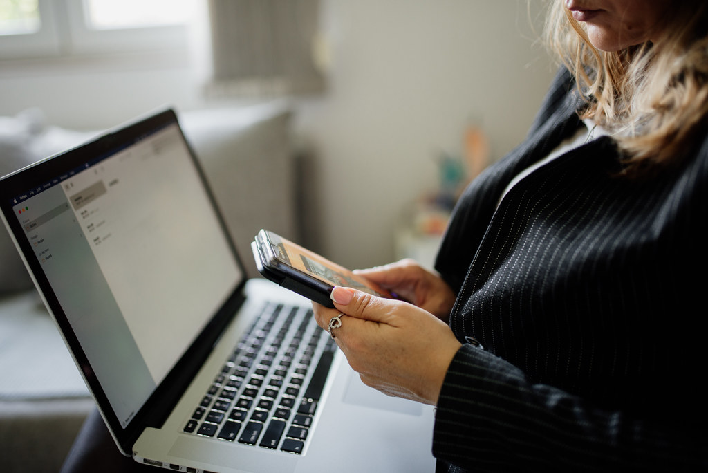 A professional in formal attire working on a laptop and phone
